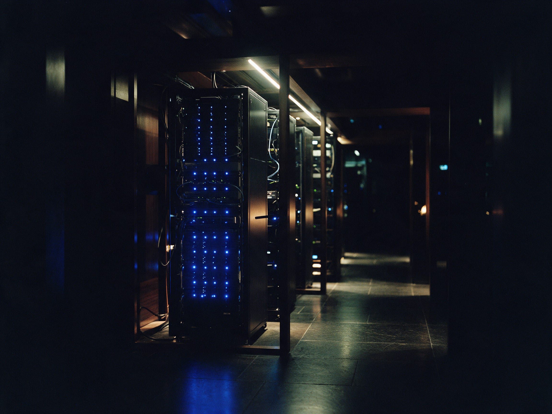 A dark server aisle lit by rows of blue status lights