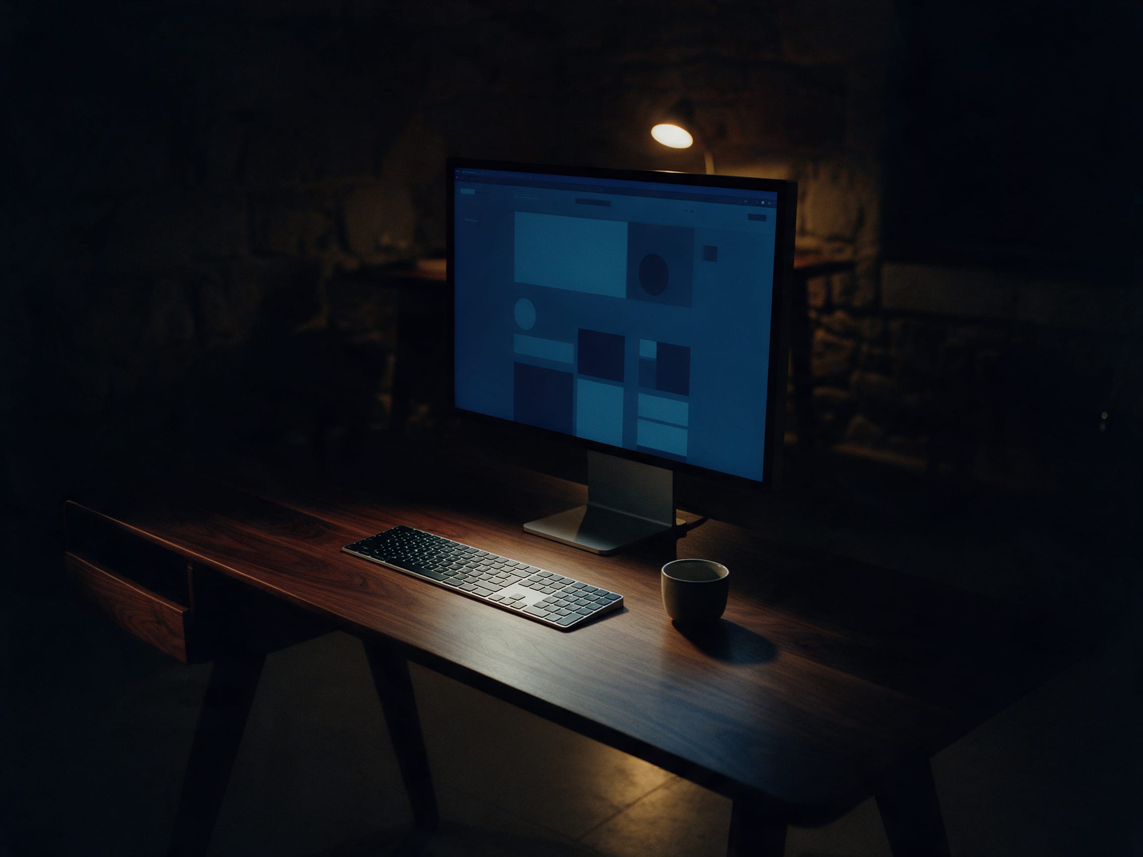 A monitor glowing over an abstract website layout on a dark studio desk at night
